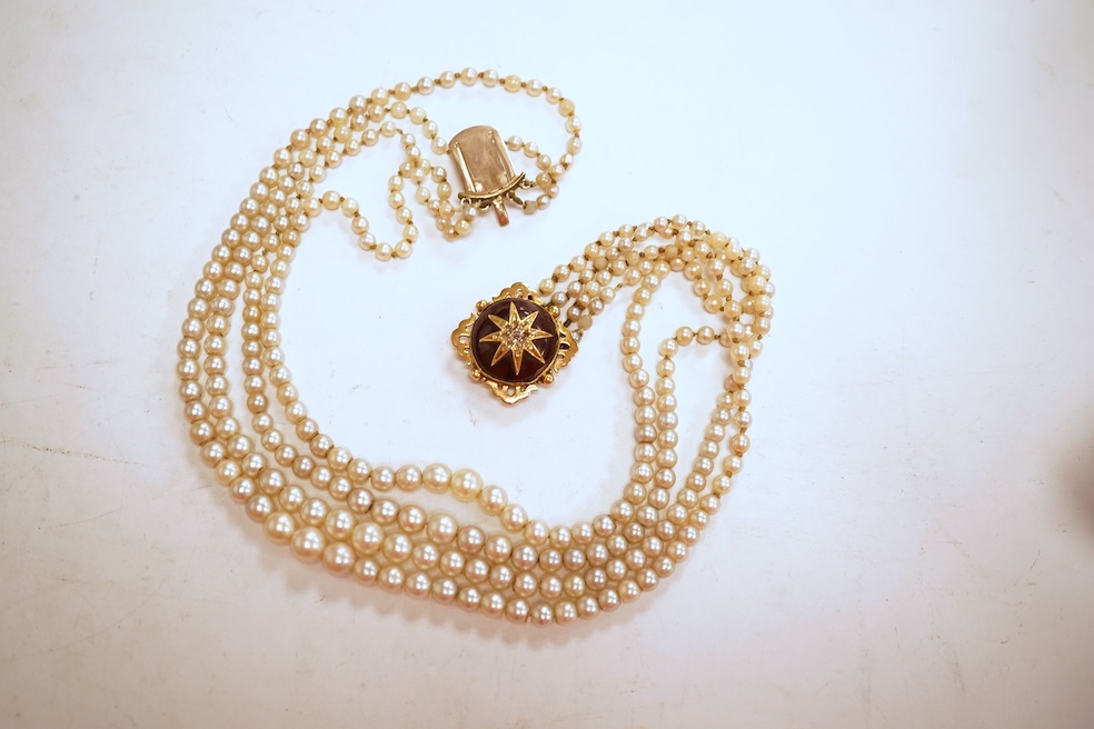 Two necklaces, comprising: a three-strand cultured pearl necklace, to a cabochon garnet and diamond clasp, length 34cm; and a paste and gilt metal pendant on a gold chain, chain length 44cm, stamped 14K, gross weight of
